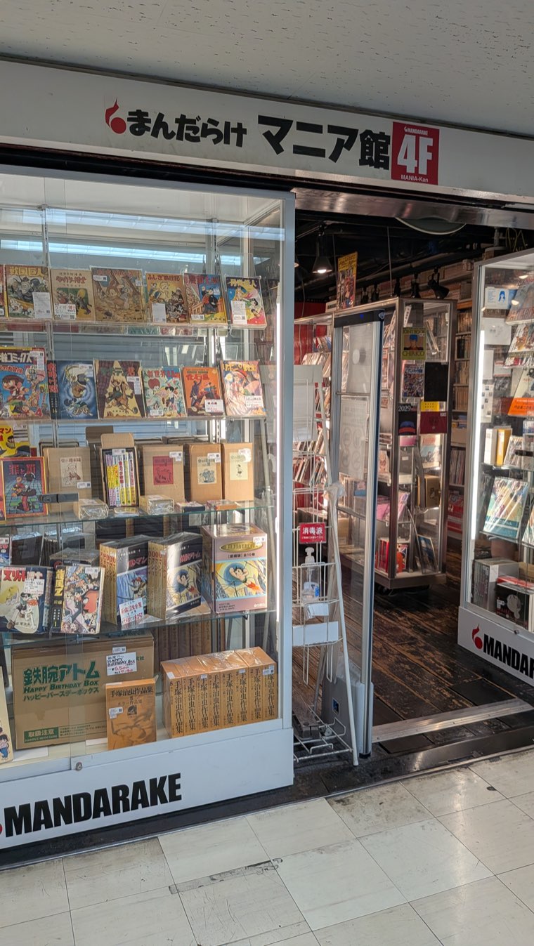 Ladenfront von Mandarake Mania-kan im 4. Stock, alte Manga-Bände flach hinter Schiebevitrinen ausgelegt
