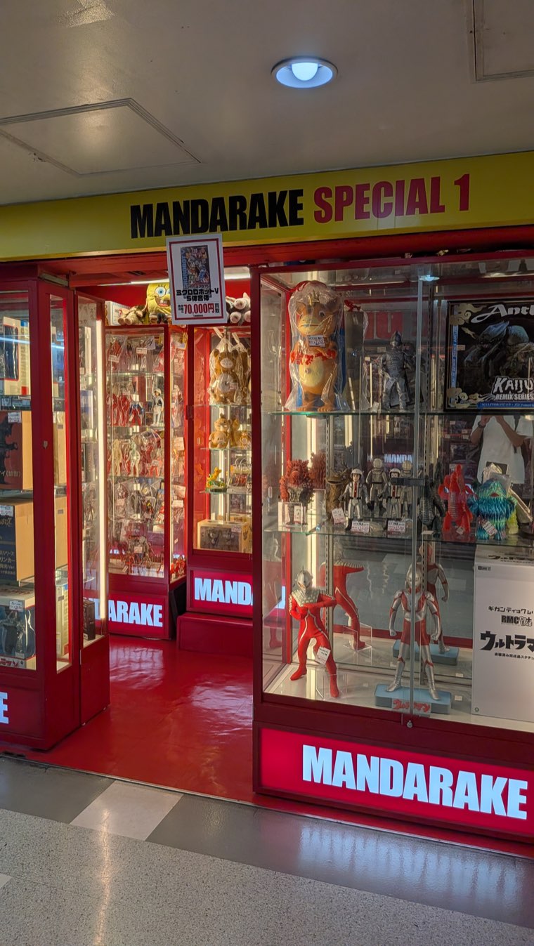 Rote Ladenfront von Mandarake Special 1 mit Vitrinen voller Vinylfiguren von Ultraman und anderen Kaiju und Robotern