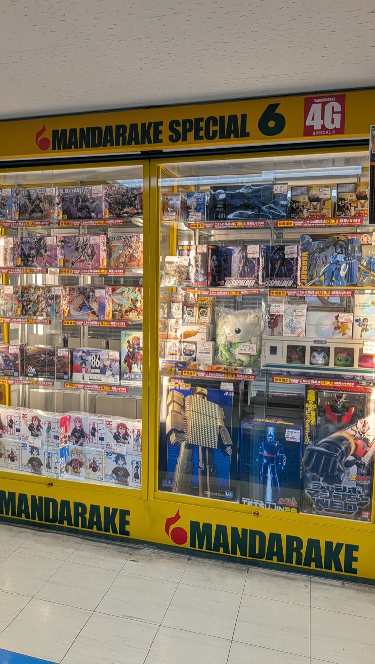 Ladenfront von Mandarake Special 6 im 4. Stock mit gelben Vitrinen voller verpackter Roboter-Bausätze und Figuren